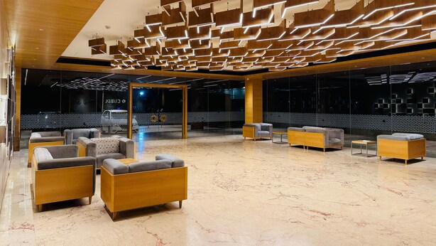 A modern lobby with a geometric ceiling design, marble flooring, and contemporary seating arrangements. - Cubix Hotel (Hubli)