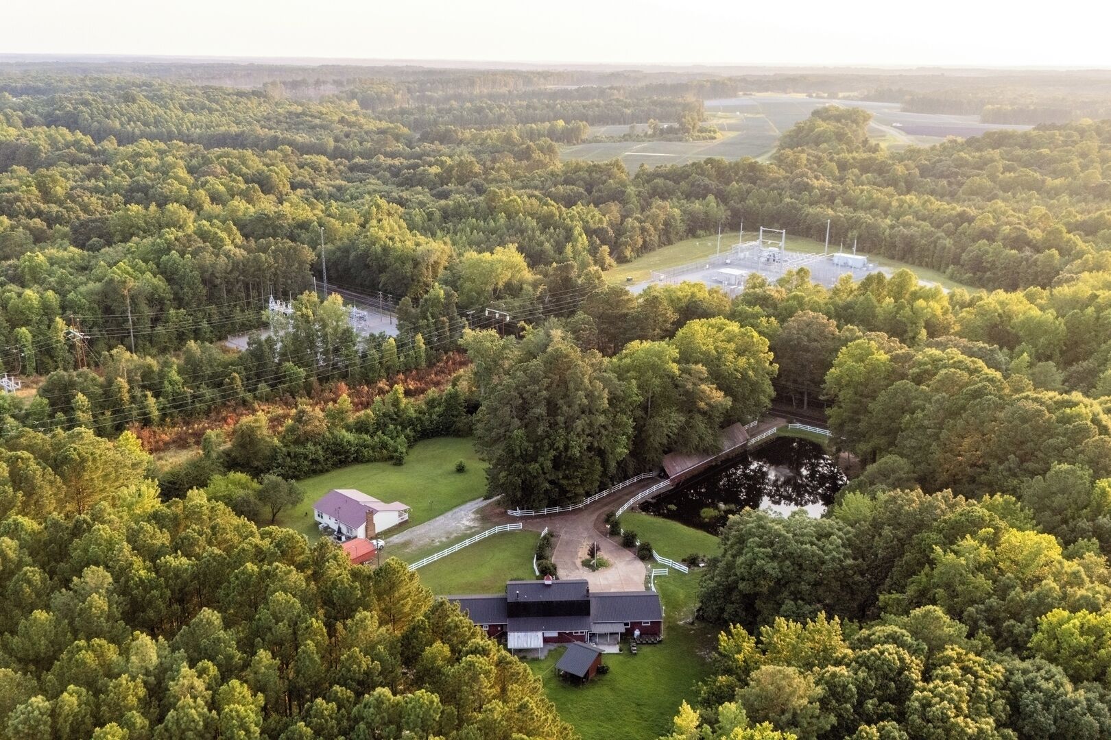 An aerial view of a rural property with a large house, a fenced paddock, and a small building.
