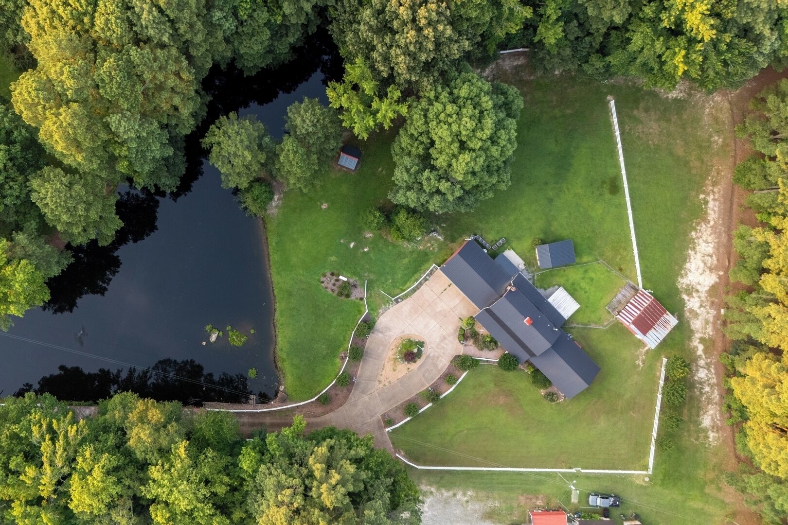 Ett flygbildsfoto av en bostadsfastighet med ett stort hus, en damm och omgivande grönska.