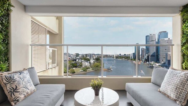 A balcony with a city view, two grey sofas, a round table with a plant, and a railing. - Sweet! 1Bed, 1Bath, 1Car, VIEWS ~ CBD (Brisbane City)