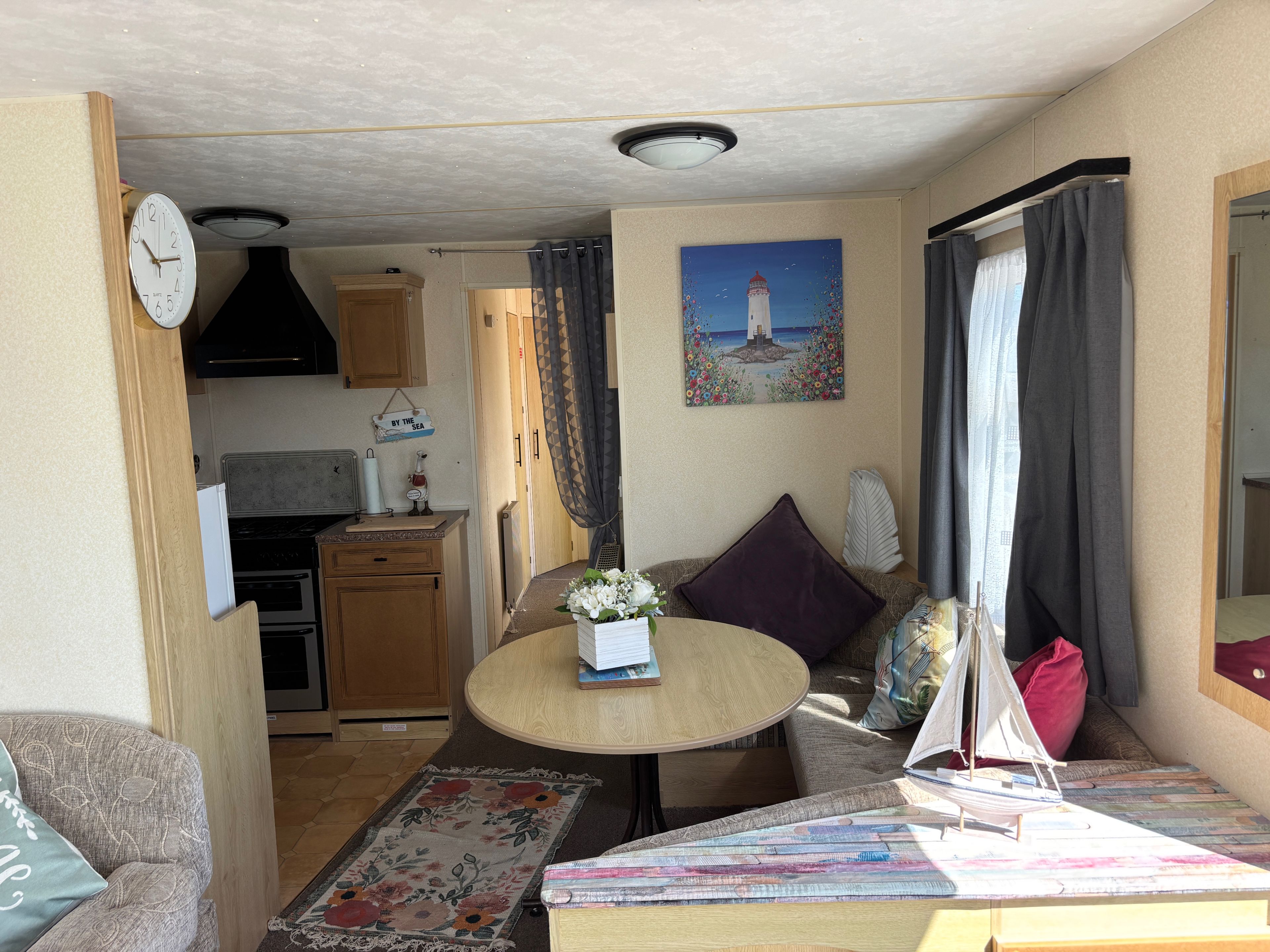 Een compacte woonruimte met een kitchenette, een eethoek en een zithoek met een model zeilboot.
