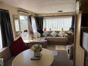 A cozy living area with a sofa, a coffee table, and a TV. - 2 Bed Caravan - Sleeps 6 - Dogs - Parking - Wifi (point)