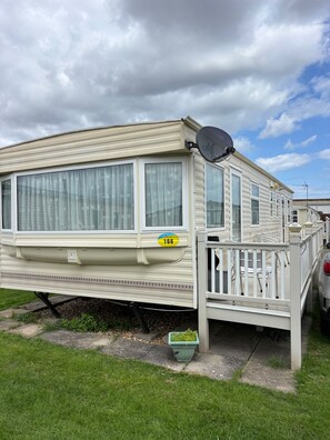 A mobile home with a deck, large windows, and a satellite dish. - 2 Bed Caravan - Sleeps 6 - Dogs - Parking - Wifi (point)