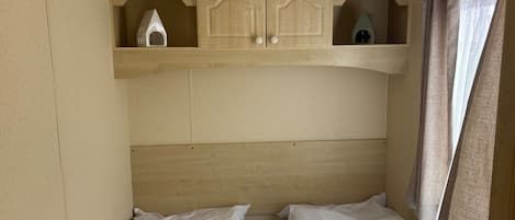 A bedroom with two beds, a wooden headboard, and a small cabinet with decorative items.