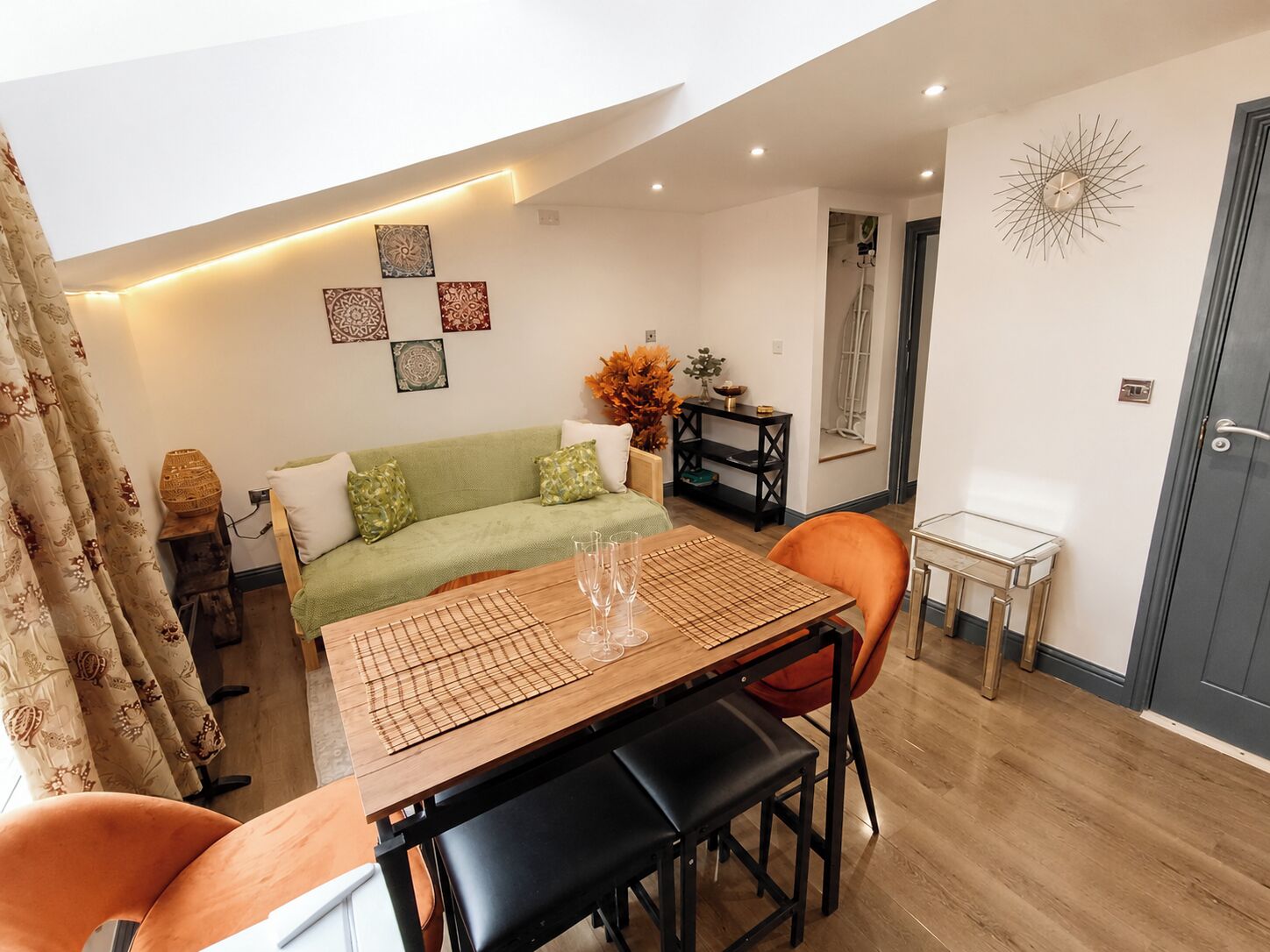 A modern living room with a dining table, sofa, and decorative wall art.