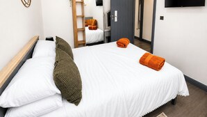 Ein Hotelzimmer mit einem Bett, einem Fernseher, einem Kleiderschrank und einer Tür zu einem weiteren Raum.