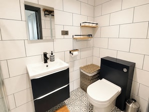 Une salle de bain moderne avec un lavabo blanc, un meuble-lavabo noir, des toilettes et une poubelle.