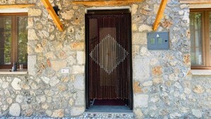 A stone building with a wooden pergola entrance, a metal gate, and a small window on the right. - Spacious Stone Villa in the heart of Kayakoy, Overlooking the historic ruins. (Fethiye)