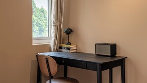 A small, well-lit room with a desk, chair, and an air conditioner mounted on the wall.