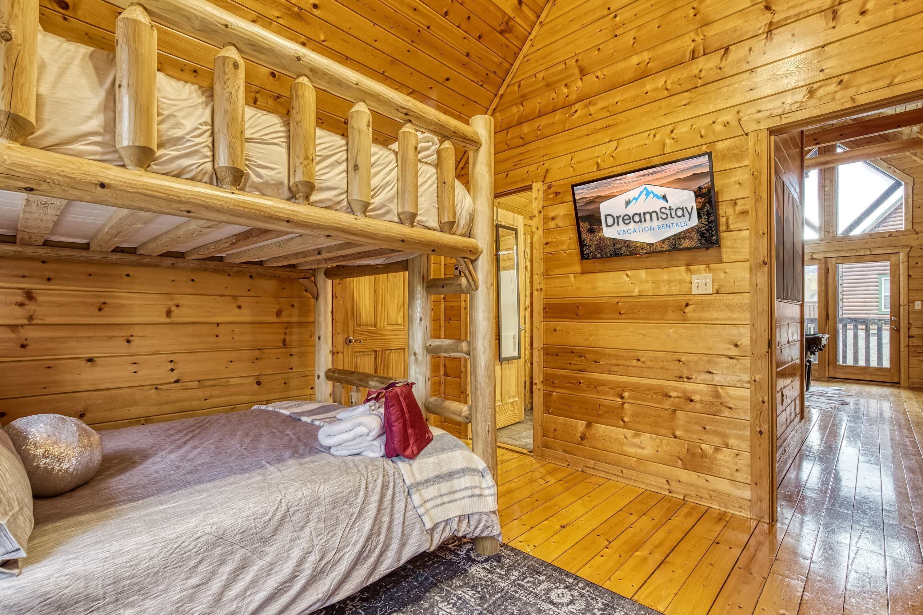 Une cabane en bois avec des lits superposés, une télévision et une enseigne indiquant « DreamStay, locations de vacances ».