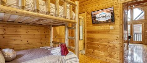 Une cabane en bois avec des lits superposés, une télévision et une enseigne indiquant « DreamStay, locations de vacances ».