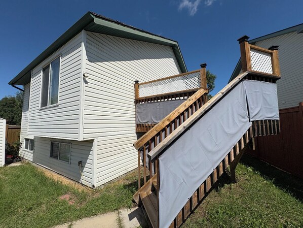 Una casa de un piso con una terraza de madera y una escalera cubierta.