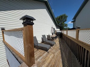 A wooden deck with a white fence, a wooden railing, and a small table with chairs.