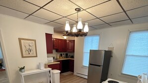 A compact kitchen with a white stove, a refrigerator, and wooden flooring.