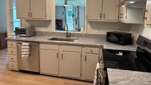 A modern kitchen with white cabinets, a built-in oven, a microwave, and a stainless steel range hood. - Chic 3 Bedroom Midcentury Modern Retreat in Wonderful Greensboro (Greensboro)
