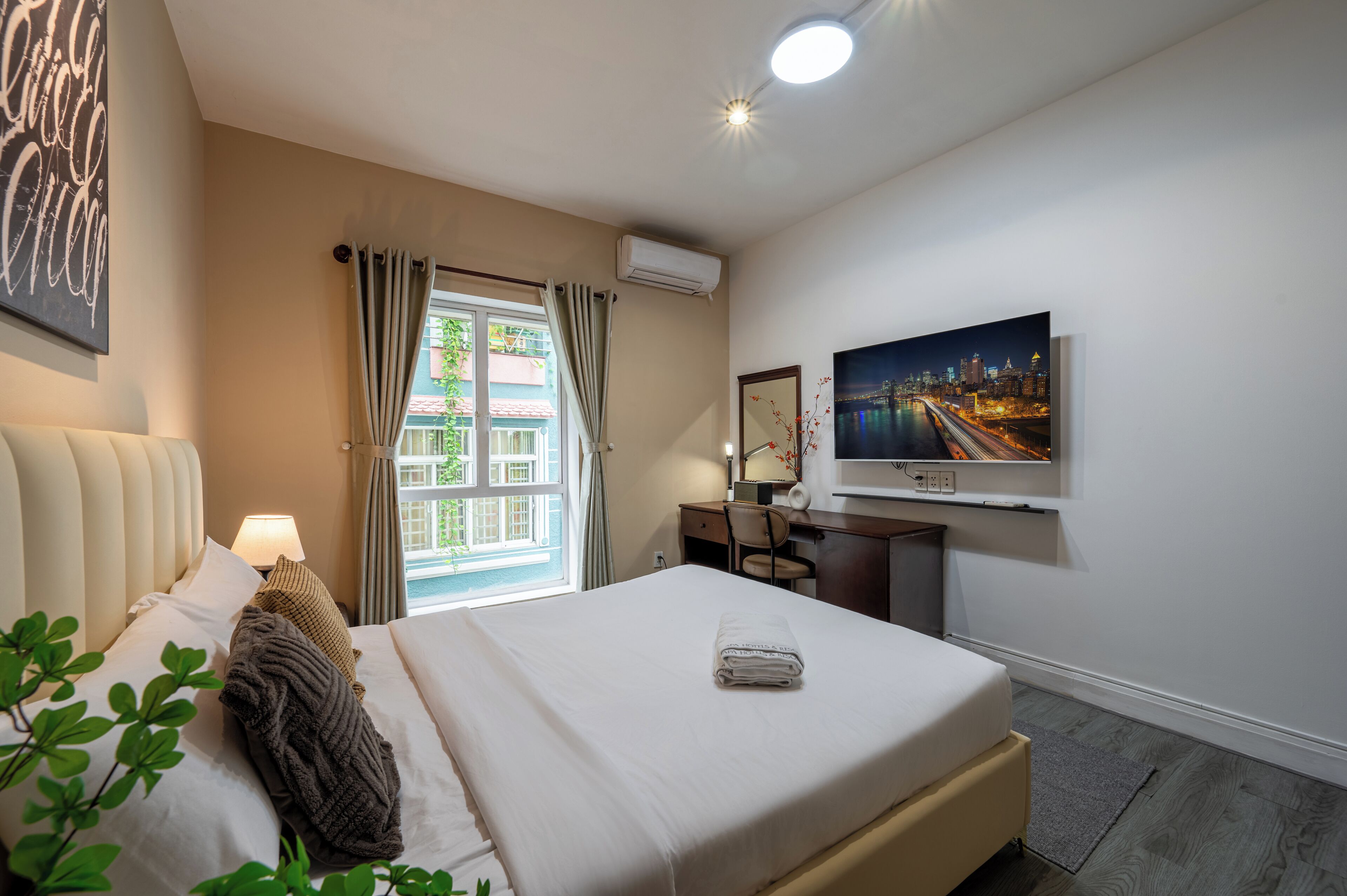 A hotel room with a bed, a desk, a TV, and a window with curtains.
