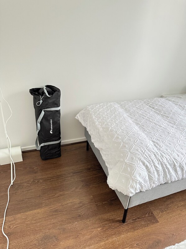 Une chambre à coucher avec un lit, un mur gris et un plancher en bois.