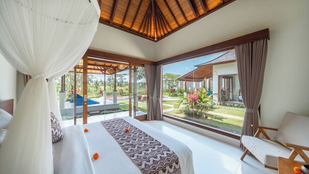 A bedroom with a large bed, a canopy, and a view of a garden and pool. - Sunrise Terrace Ubud Vila by Nagisa Bali (Ubud)