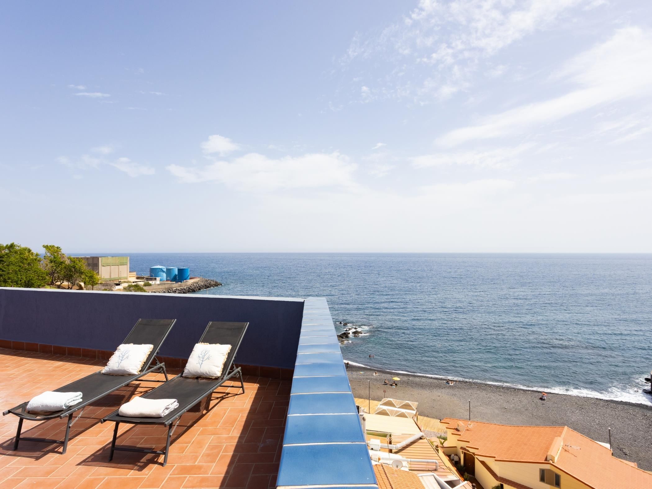 Une terrasse sur le toit, dotée de chaises longues et offrant une vue sur la mer.