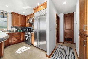 A modern kitchen with wooden cabinets, stainless steel appliances, and a patterned rug.