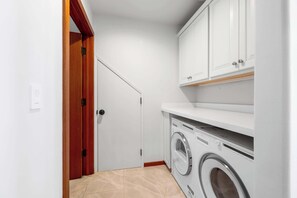 Un lavadero con lavadora, armarios blancos y una puerta de madera.