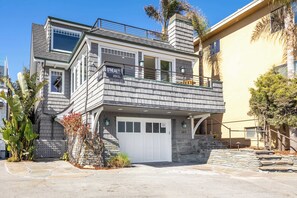 Una casa de dos pisos con garaje, escalones de piedra y un balcón.