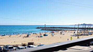 A beach with boats, tents, and cars.