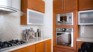 Cozinha moderna com eletrodomésticos de aço inoxidável, armários de madeira e bancada de granito.