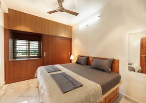 Un dormitorio con cama, armario de madera, ventilador de techo y ventana con persianas.