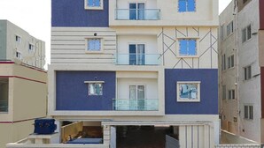 A multi-story residential building with balconies, a garage, and a brick entrance. - Enjoyable building with AC in vibrant Hyderabad (Hyderabad)