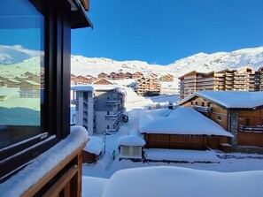 Ein schneebedecktes Bergresort mit Holzbauten und blauem Himmel.