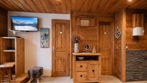 Interior em madeira com lareira, televisão na parede e decoração rústica.