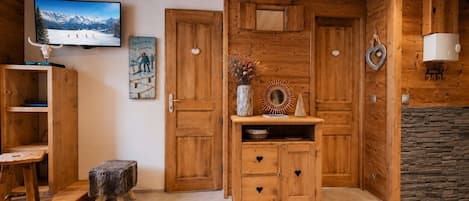 A wooden interior with a fireplace, a television mounted on the wall, and a rustic decor style.