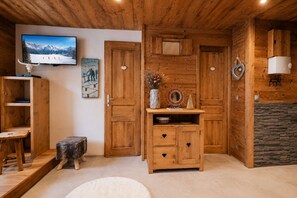Ein Holzinterieur mit Kamin, einem an der Wand montierten Fernseher und einer rustikalen Einrichtung.