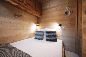 Ein Zimmer in einer Holzhütte mit einem Bett, zwei Kissen, einer Wandleuchte und einer herzförmigen Dekoration.