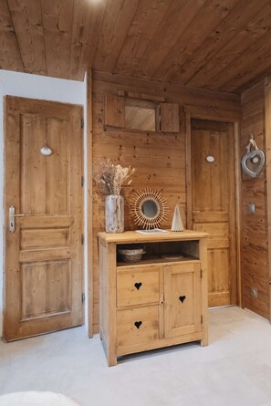 Un interior de madera con un aparador, un espejo y un florero con flores secas.