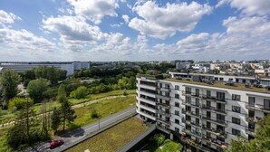 En moderne lejlighedsejerforening med flere balkoner, et grønt tag og udsigt over en by med forskellige bygninger.