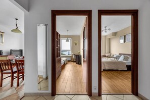 A modern apartment with a dining area, a bedroom with a large bed, and a study area with a desk and chair.