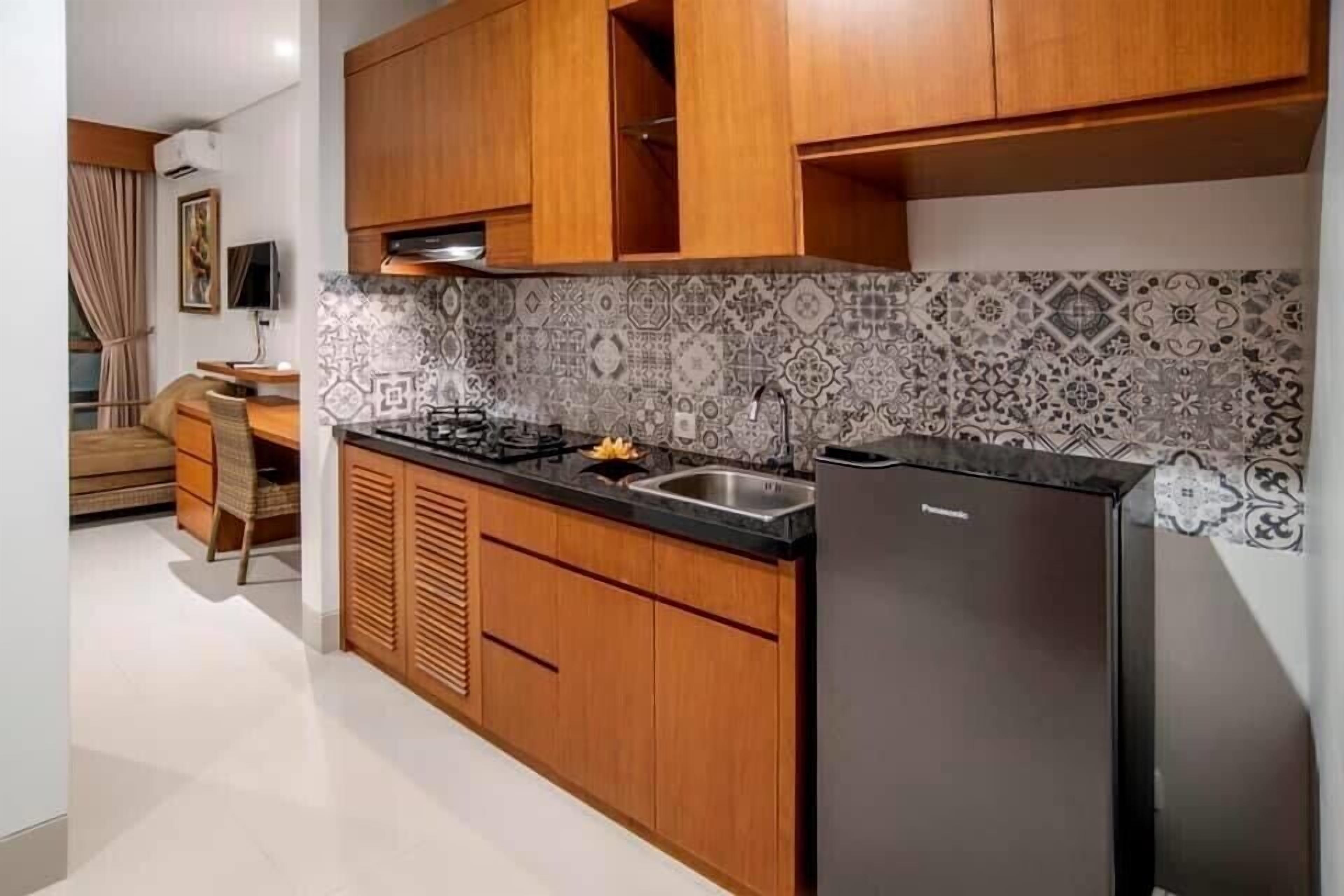 A compact kitchen with wooden cabinets, a black countertop, and a patterned backsplash.