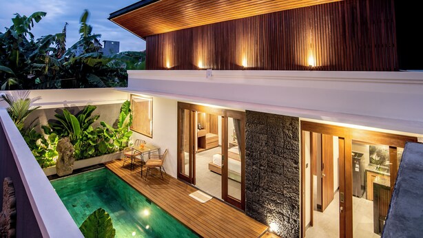 Une maison moderne dotée d’une piscine, d’une terrasse en bois et d’un intérieur bien éclairé.