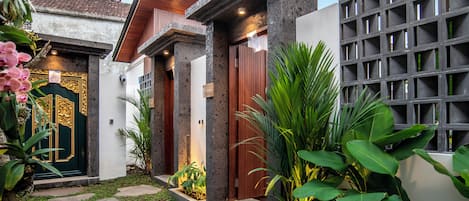 A modern building with a green door, a wooden door, and a grey wall with a grid pattern.