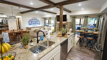 A spacious kitchen with granite countertops, a dishwasher, and a dining area with bar stools.