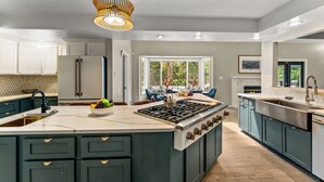 A modern kitchen with a central island, built-in appliances, and a large window providing natural light. - 7k sq/ft! Gym, Theatre, Hot Tub, Sauna, Game Room, Golf, Sleeps 28 - Family Fun! (Colorado Springs)