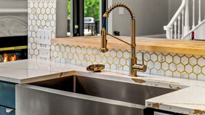 A kitchen with a stainless steel sink, a gold faucet, and a honeycomb-patterned backsplash. - 7k sq/ft! Gym, Theatre, Hot Tub, Sauna, Game Room, Golf, Sleeps 28 - Family Fun! (Colorado Springs)