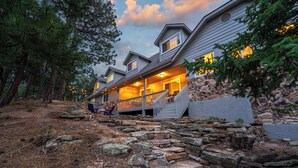 A multi-story lodge with a stone retaining wall and a porch. - 7k sq/ft! Gym, Theatre, Hot Tub, Sauna, Game Room, Golf, Sleeps 28 - Family Fun! (Colorado Springs)