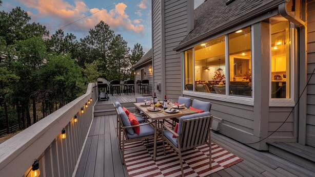 A deck with outdoor furniture, a dining table, and string lights. - 7k sq/ft! Gym, Theatre, Hot Tub, Sauna, Game Room, Golf, Sleeps 28 - Family Fun! (Colorado Springs)