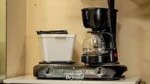 Una cafetera con un depósito blanco y una jarra negra sobre una superficie blanca.