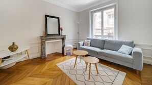 A living room with a fireplace, a grey sofa, a small round table, and a herringbone-patterned rug. - République Of City Paris (Paris)