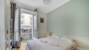 A bedroom with a bed, a window with curtains, a small balcony, and a wall-mounted picture. - République Of City Paris (Paris)