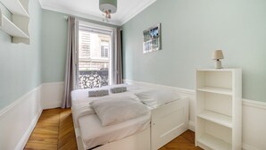 A bedroom with a bed, a window with curtains, a wall-mounted picture, and a bedside table with a lamp. - République Of City Paris (Paris)